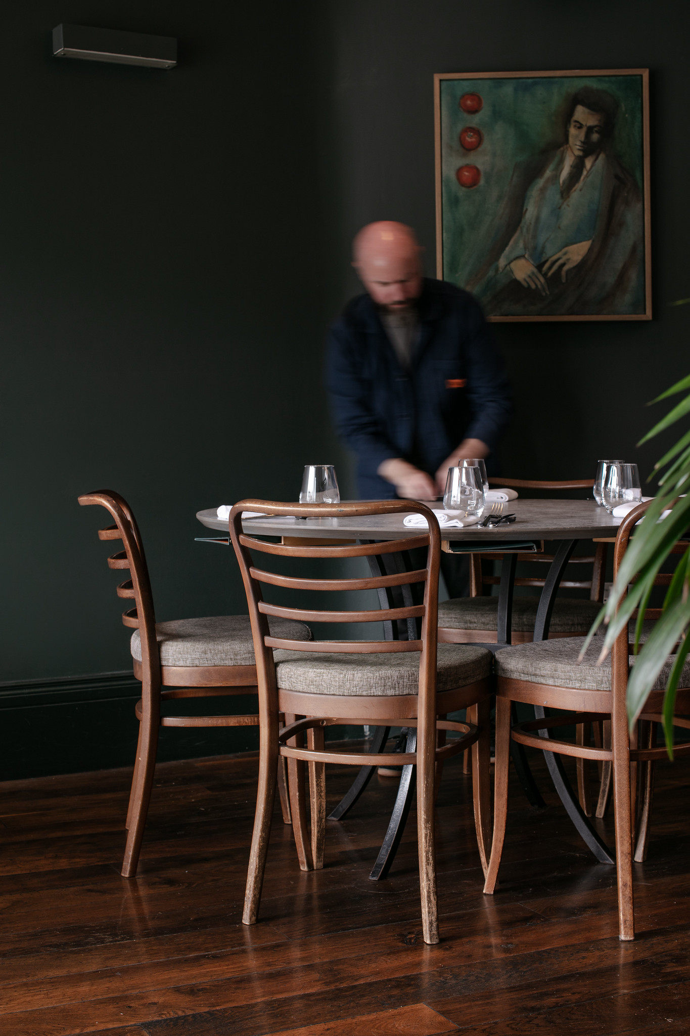 A member of staff setting a table in the dark green dining room at Paradiso in Cork